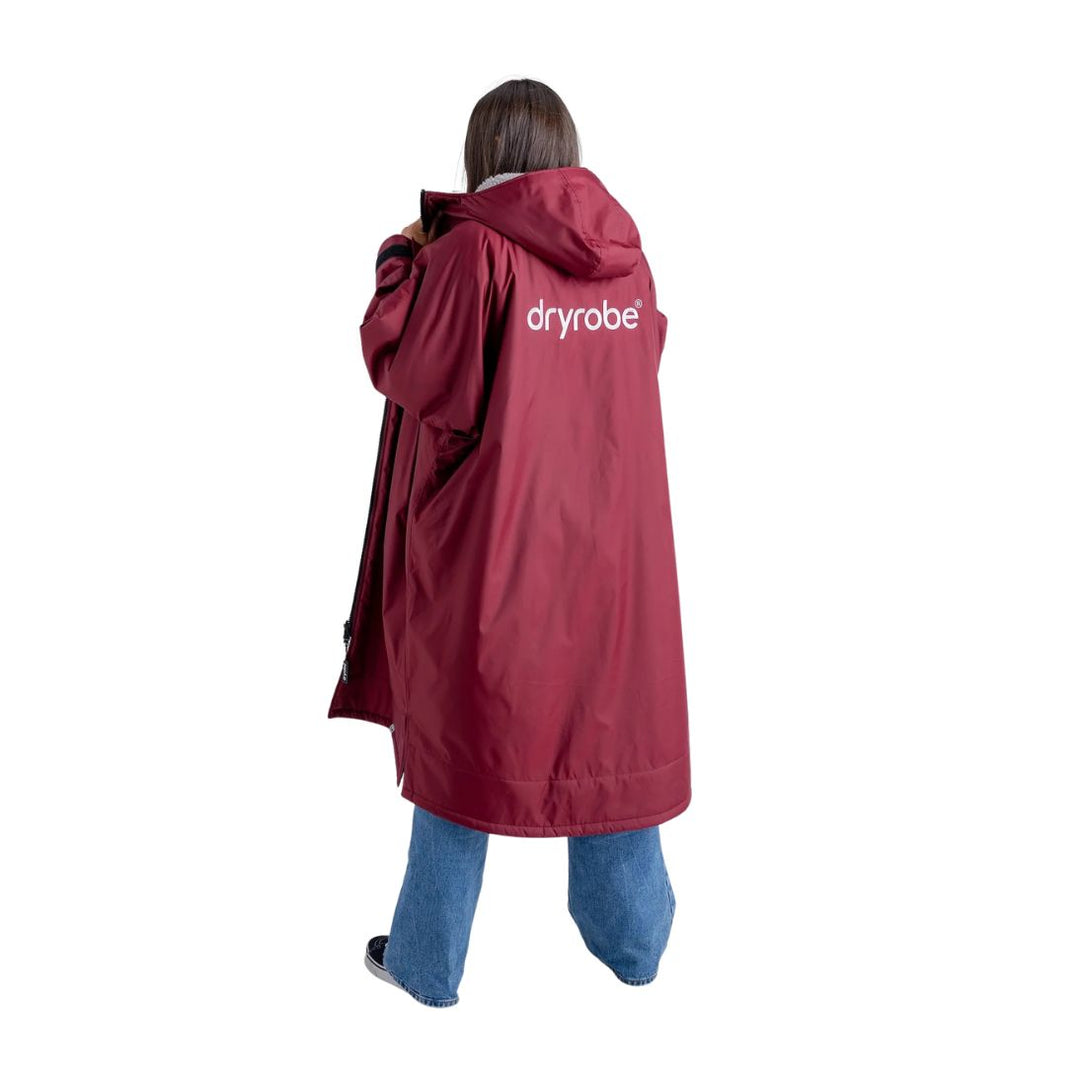Person wearing a red 'dryrobe' raincoat on a white background